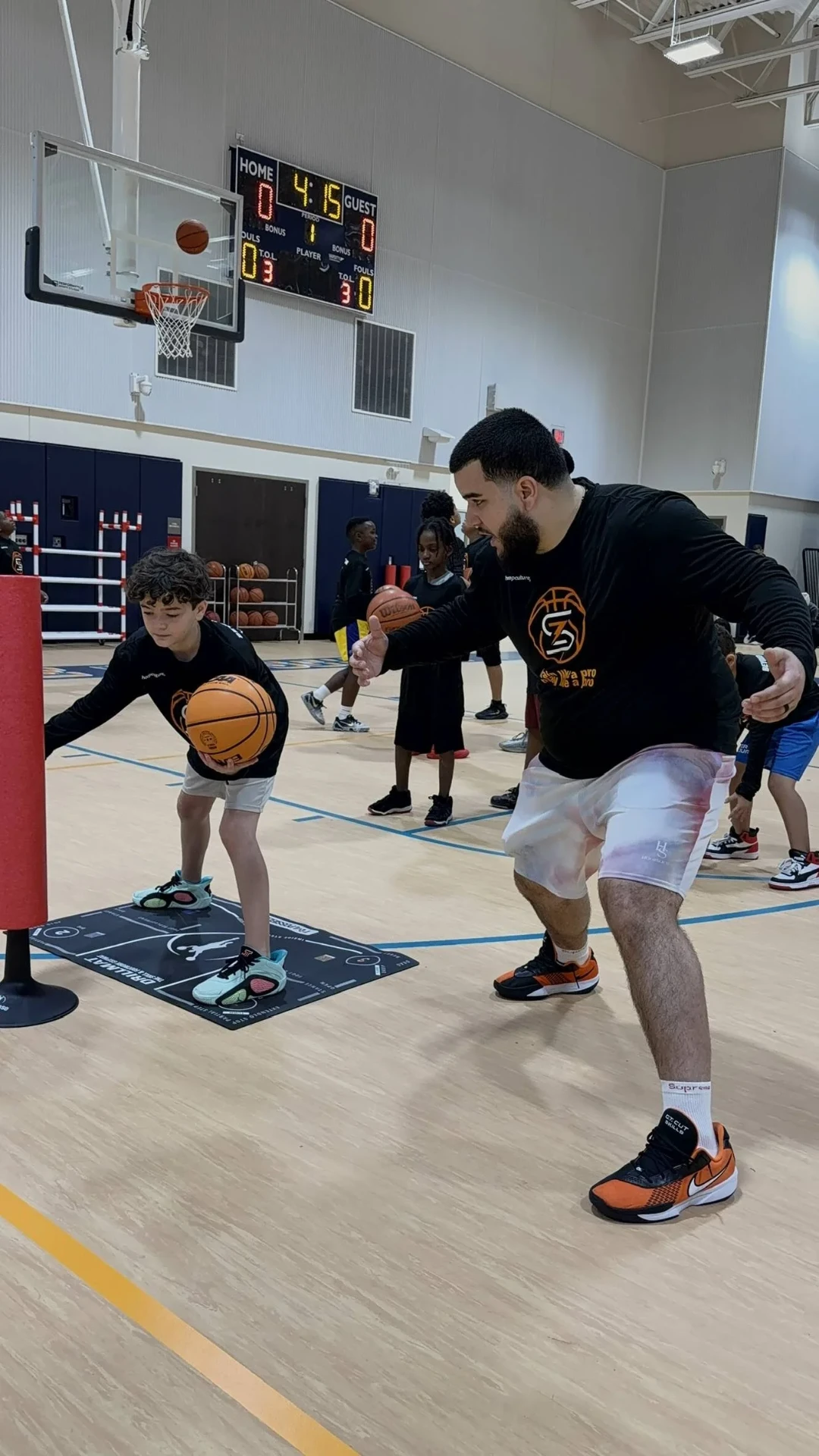 Coach guiding a young player through a ball-handling drill