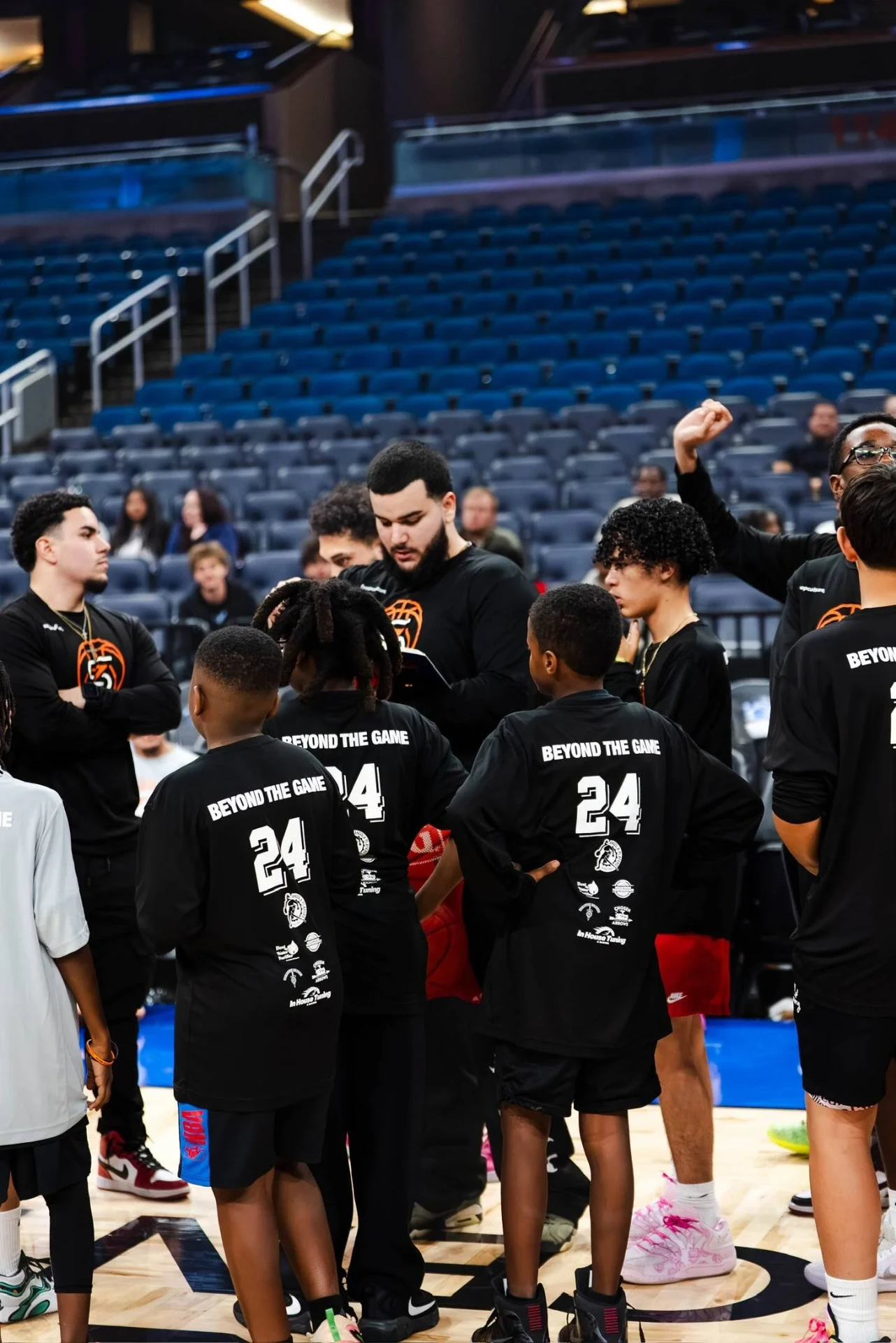 Players in Beyond The Game shirts huddled courtside in an arena