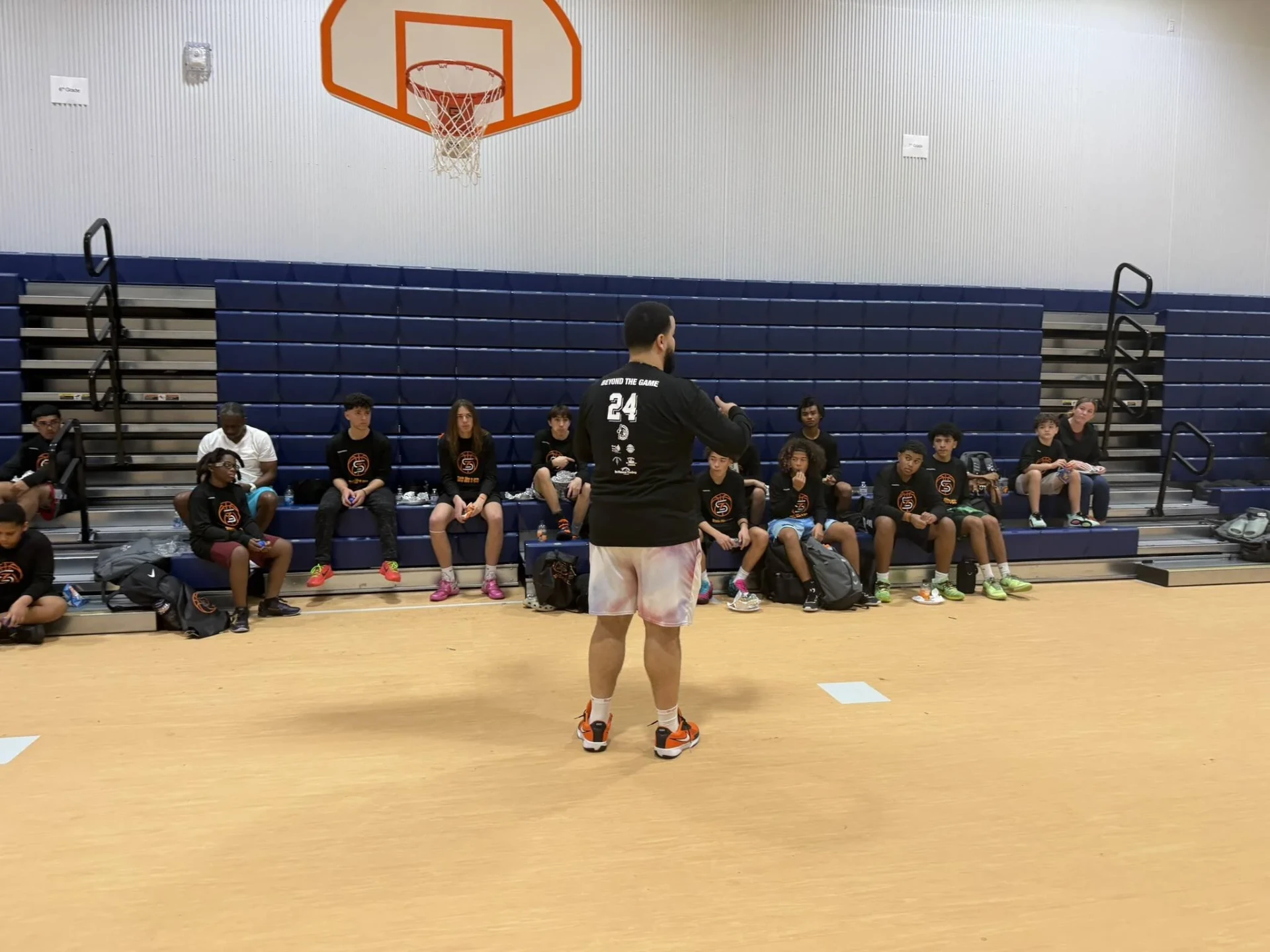 Coach teaching a seated group of campers in the gym