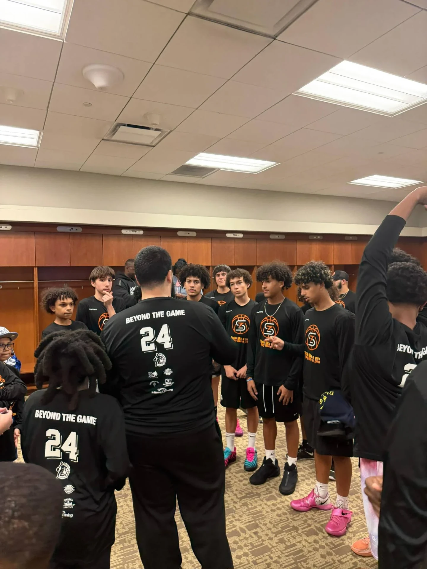Coach speaking to players wearing Beyond The Game jerseys in the locker room