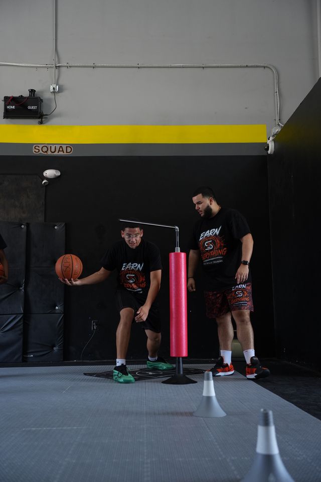 Coach teaching shooting mechanics to a young basketball player one on one